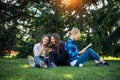 Young girls relax in the park on green grass. Students spend their free time in nature, read books, communicate in social networks Royalty Free Stock Photo