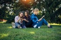 Young girls relax in the park on green grass. Students spend their free time in nature, read books, communicate in social networks Royalty Free Stock Photo