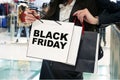 Young girls with shopping bags in store. The inscription Black Friday on a white package. Girl looks at their purchases in your Royalty Free Stock Photo