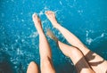 Young girls sit on the edge of swimming pool and chat with their feet in the water, girls splash their feet in the pool Royalty Free Stock Photo