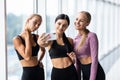 Happy young girls in sportswear taking selfie in gym. Three female friends in healthclub taking selfie with mobile phone Royalty Free Stock Photo