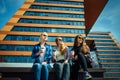 Young girls in sunglasses sitting on a city street and drink coffee to take away. Three cute women have a coffee break together Royalty Free Stock Photo