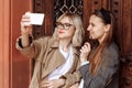 Young girls taking selfies on the phone. selfie photos for social media on smartphone on the street background. Surprise face, Royalty Free Stock Photo