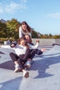 3 Young girls teenage schoolgirls ride skateboard summer park. Casual wear sweater jeans. Emotions happiness, fun