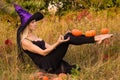 Young glad girl in witch costume practicing yoga