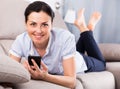 Young glad woman lying with mobile phone