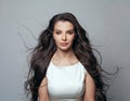 Young glamorous woman posing in the studio on a gray background. Wind in female hair. Beautiful brunette portrait