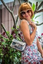 Young glamour woman wearing flower dress posing with luxury handmade snakeskin python handbag. Beautiful stylish girl Royalty Free Stock Photo