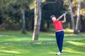 Young golf player hits a driver shot from the tee on a golf course. Concept: competition, concentration, sport, wealthy life. Royalty Free Stock Photo