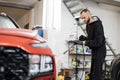 Young good-looking bearded man worker washing luxury red crossover car on a car wash Royalty Free Stock Photo