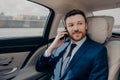 Young good looking businessman taking ride to conference while talking on phone Royalty Free Stock Photo