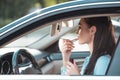 Young good-looking woman applying lipstick in car, using a sun Royalty Free Stock Photo