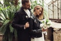 Young gorgeous smiling woman in black leather jacket and dress with little bouquet of white flowers in hand closing eyes Royalty Free Stock Photo