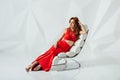 Young gorgeous woman in red dress on the chair Royalty Free Stock Photo