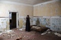 Young goth woman standing in room of abandoned house