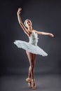 A young graceful ballerina dressed in professional attire, pointe shoes and a white tutu, demonstrates dance skills. Beautiful
