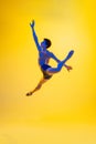 Young and graceful ballet dancer isolated on yellow studio background in neon light. Art, motion, action, flexibility