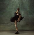 Young graceful tender ballerina on dark studio background