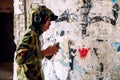 Young graffiti artist in hoodie spraying the wall