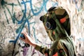 Young graffiti artist in hoodie spraying the wall. Street art concept