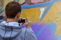 A young graffiti artist photographs his completed picture on the wall Royalty Free Stock Photo