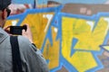 A young graffiti artist photographs his completed picture on the wall Royalty Free Stock Photo