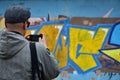 A young graffiti artist photographs his completed picture on the wall Royalty Free Stock Photo