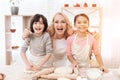 Young grandmother with small grandchildren is laughing in kitchen. Noses dirty with flour.