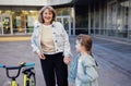 Young grandmother teaches her cute little granddaughter to ride a bicycle