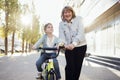 Young grandmother teaches her cute little granddaughter to ride a bicycle