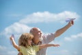 Young grandson and old grandfather with paper plane over blue sky and clouds. Men generation granddad and grandchild. Royalty Free Stock Photo