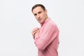 A young greedy man in pink shirt hides something in his hands Royalty Free Stock Photo