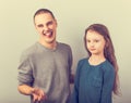 Young grimacing teen father have a dialog with his small school girl daughter and showing the tongue. Happy joyful emotions on