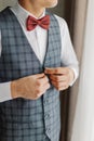 Young groom buttoning his jacket near the window on his wedding day Royalty Free Stock Photo