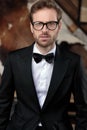 Young groom looking forward while wearing tuxedo and glasses