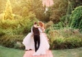 Young groom in a suit carries in arms his bride, wearing a long magnificent luxurious white dress, walking at amazing Royalty Free Stock Photo