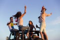 Young group having fun on the beach and dancing in a convertible car Royalty Free Stock Photo