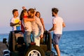 Young group having fun on the beach and dancing in a convertible car Royalty Free Stock Photo