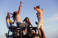 Young group having fun on the beach and dancing in a convertible car Royalty Free Stock Photo