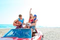 Young group having fun on beach playing guitar Royalty Free Stock Photo