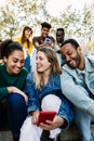 Young group of people sitting outdoors having fun using smartphones together Royalty Free Stock Photo