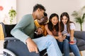 Young group of people using mobile phone device sitting together on sofa at home Royalty Free Stock Photo