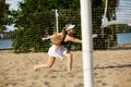 Young gsportive girl in cap and sportswear playing beach tennis, hitting ball with racket. Outdoor training on warm Royalty Free Stock Photo