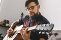 Young guitarist hipster at home with guitar sitting playing concentrated close-up Royalty Free Stock Photo