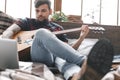 Young guitarist hipster at home playing guitar in bedroom browsing laptop close-up Royalty Free Stock Photo