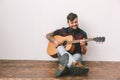 Young guitarist hipster at home sitting on the floor playing guitar smiling Royalty Free Stock Photo