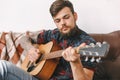 Young guitarist hipster at home sitting playing guitar serious Royalty Free Stock Photo