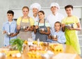 Young guy and adult woman cook pose with group of children at master class Royalty Free Stock Photo