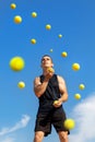 Young guy athlete juggles yellow balls outdoors. Sports concept.