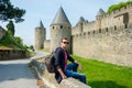 A young guy with backpack sits near fortress wall of the medieval city Carcassonne in France Royalty Free Stock Photo